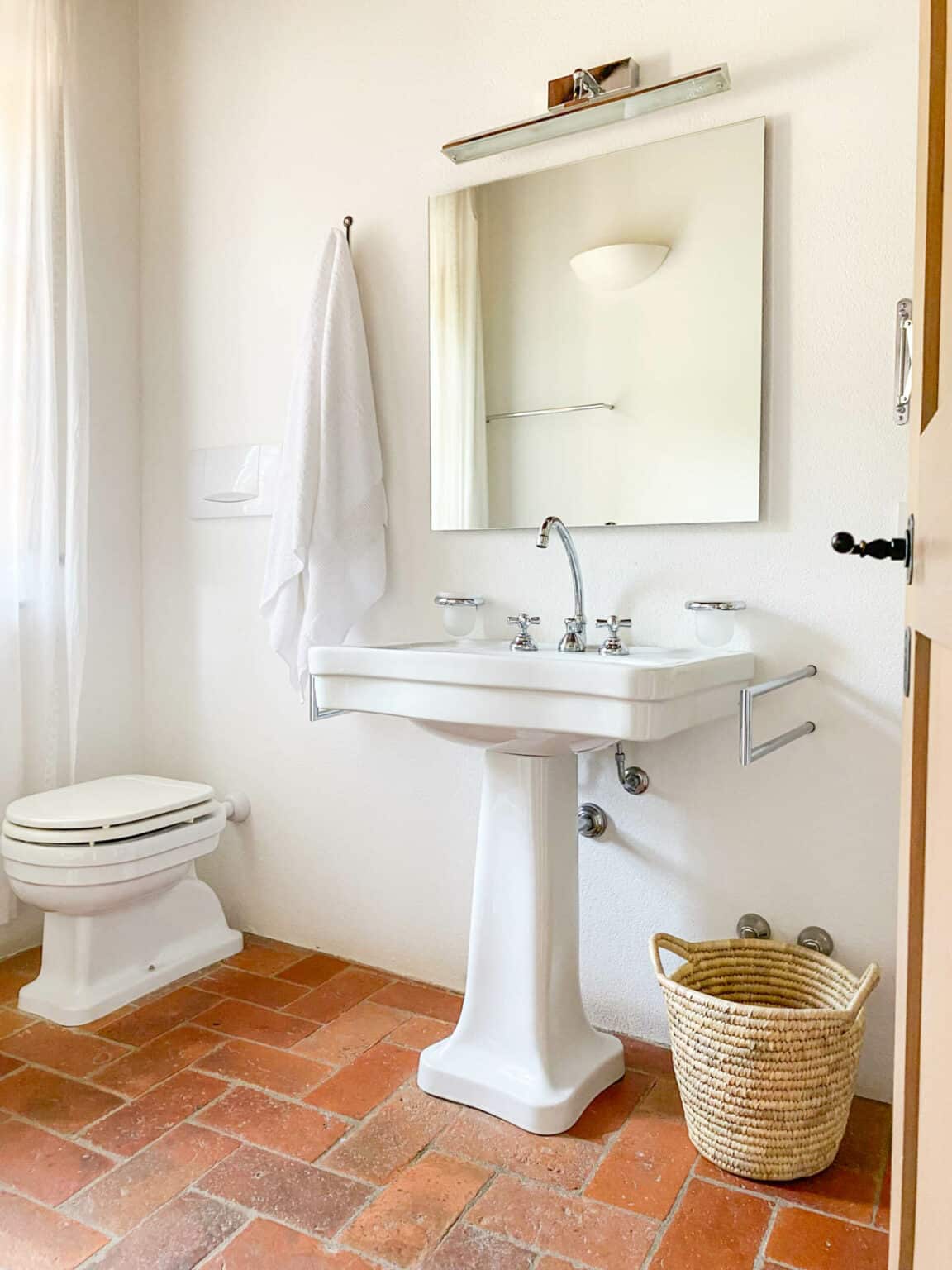 Stilvolles weißes Keramik-Waschbecken mit eleganter Armatur und Spiegel im modernen Bad des historischen Anwesens nahe Montepulciano.