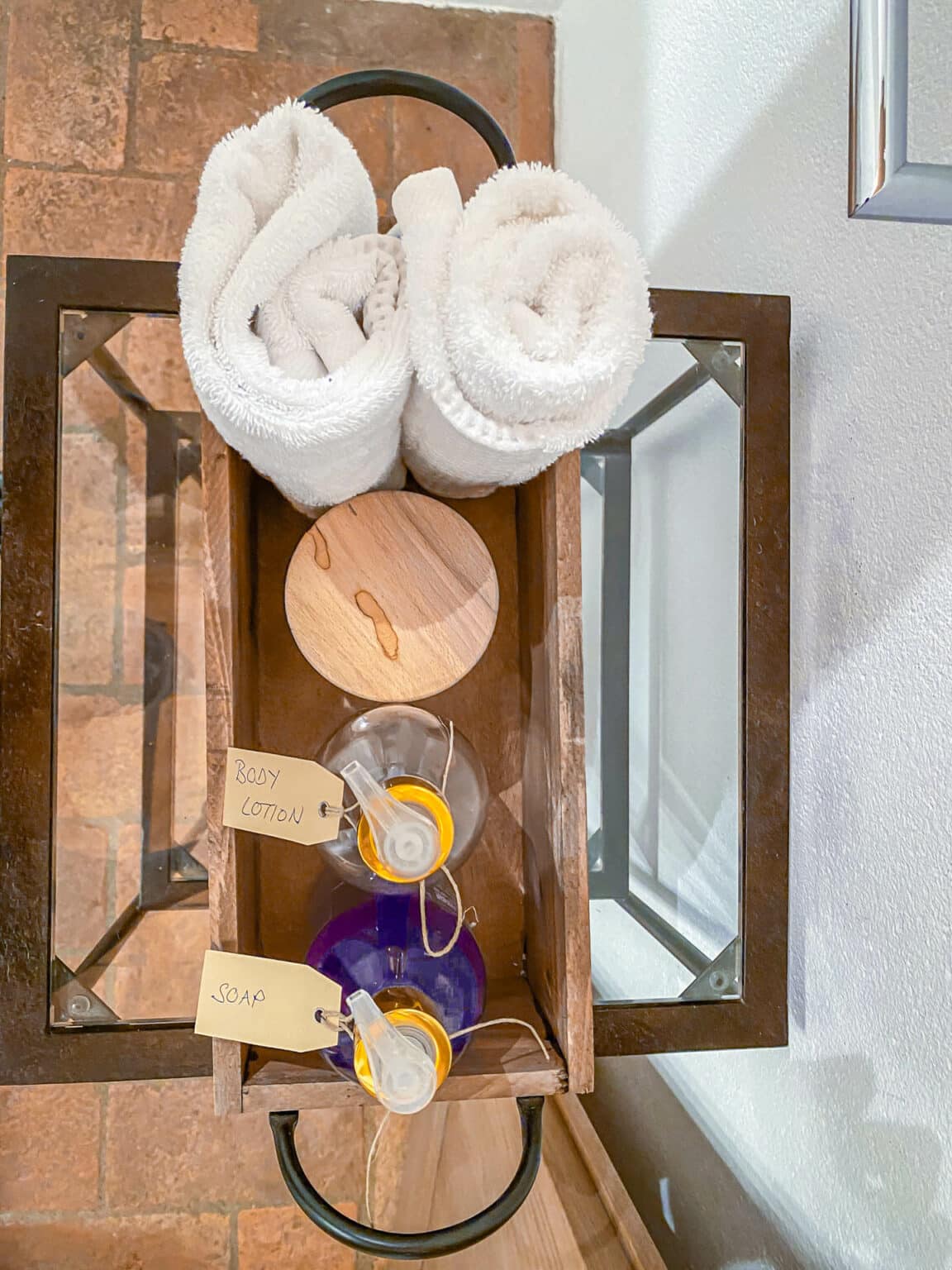 Flauschige weiße Handtücher und handgemachte Pflegeprodukte, wunderschön arrangiert auf einem rustikalen Holztablett in einem stilvollen Luxuszimmer.